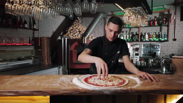 Chef Adding Grated Cheese on Pizza Base