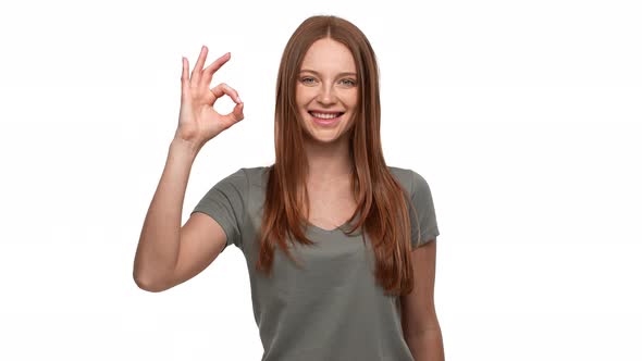 Portrait of Friendly Redhead Woman 20s Smiling and Showing Ok Sign with Gladness Isolated Over White