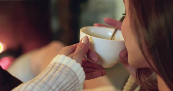 Back View of Young Woman Having Coffee While Relaxing at Home During Cold Winter. Woman Sitting on