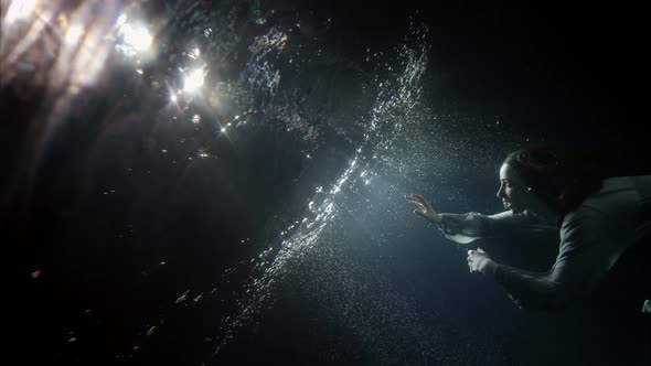 Mystery and Magic Underwater Young Woman Is Floating To Mirror Water Surface Rising Over Surface