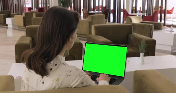 Woman searching internet sitting in hotel lobby. Tourist resting after eventful day. Green screen