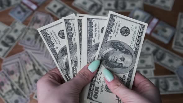 Dollars in Woman Hands on Background of Table with Money