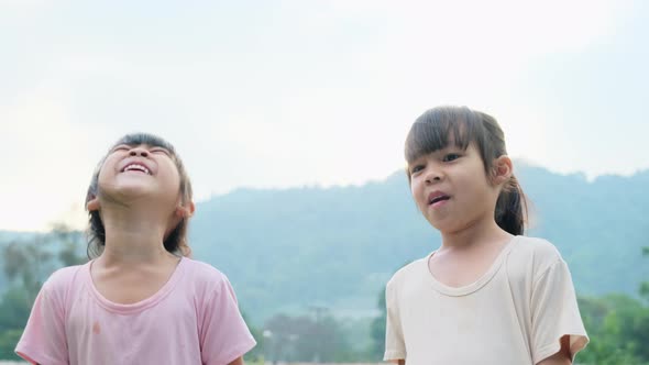 Portrait of Two cute Asian sisters smiling happily in the summer garden.