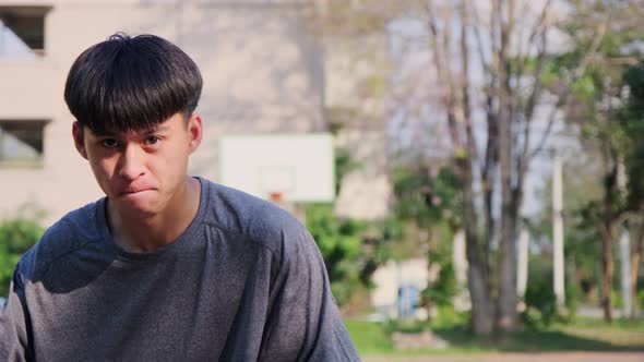 Young Asian athletic male playing basketball outdoors.