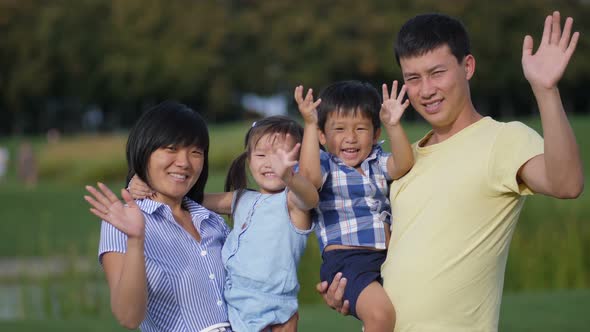 Happy Asian Family Waving Hands Together Outdoors