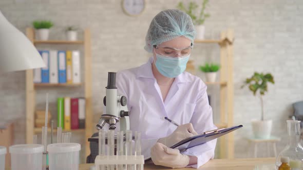 Close Up of a Female Laboratory Assistant Conducts and Records the Study Using a Microscope