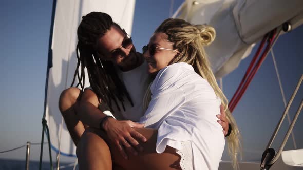 Low Angle Footage of Stylish Couple with Dreadlocks in White Clothes and Sunglasses Sitting
