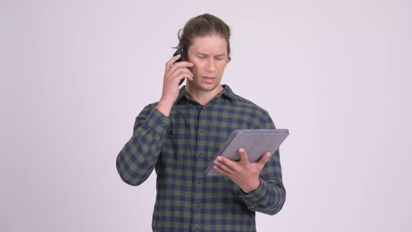 Stressed Hipster Man Talking on the Phone While Using Digital Tablet