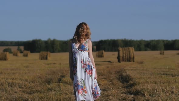 Portrait of Attractive Redhead Woman Dancing Against Background of Fields