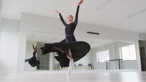 Caucasian female ballet dancer practicing ballet during a dance class in a bright studio