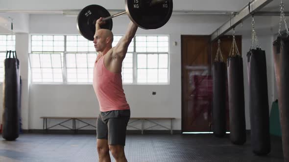 Caucasian male trainer working out with barbell at the gym