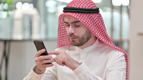Attractive Arab Businessman Using Smartphone in Office