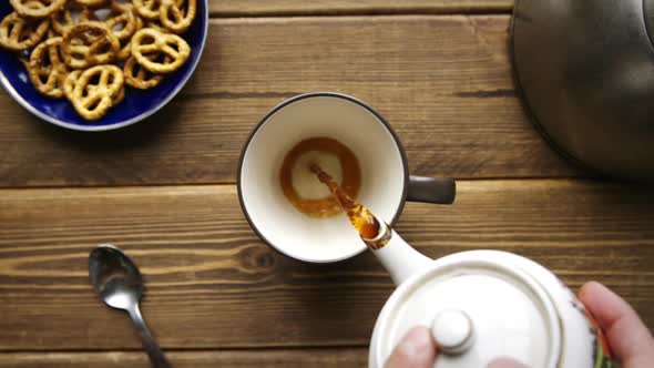 Tea Being Poured Into Cup From Ceramic Teapot