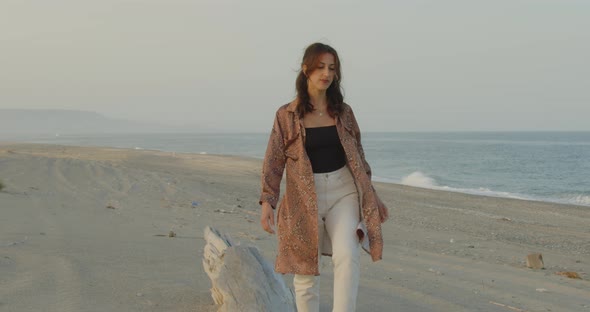 Young girl walks balancing on a log on the beach