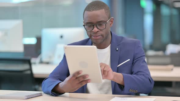 Attractive African Businessman Using Tablet in Office