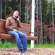 Young Caucasian Man Talking on Smartphone While Sitting on Wooden Swinging Bench in Autumn Park - VideoHive Item for Sale