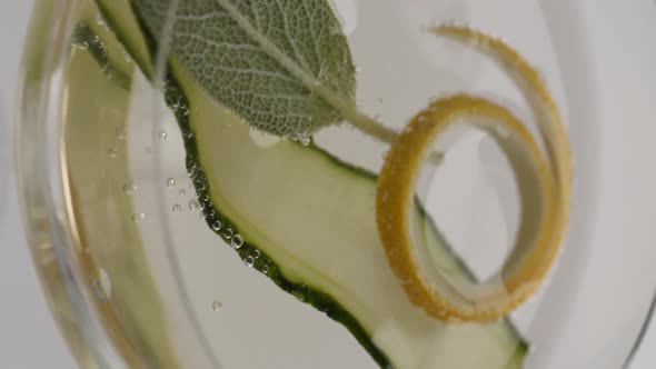 Vertical video, Close-up: lemon fells in a glass of bubbling champagne with cucumber