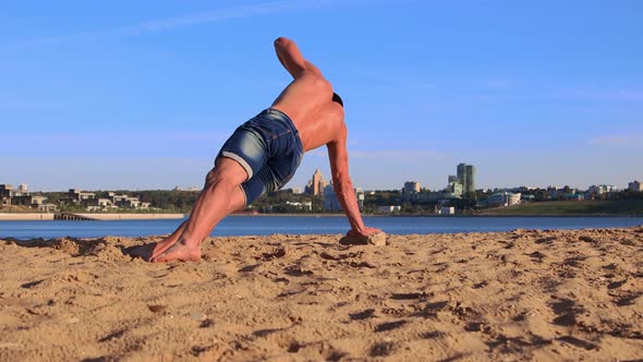 Fit Young Man Doing Sports Exercises on the Beach