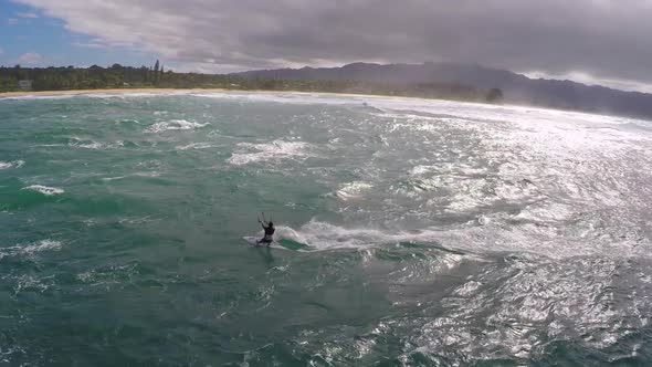 Aerial view of a man kitesurfing in Hawaii.