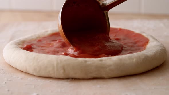 Camera follows pouring tomato sauce on a pizza dough. Slow Motion. alt