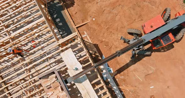 A Woodentruss Being Lifted By a Boom Truck Forklift in the Building Materials a Stack of Boards Wood