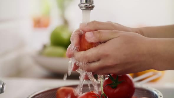 Handheld view of human hands washing fresh tomatoes