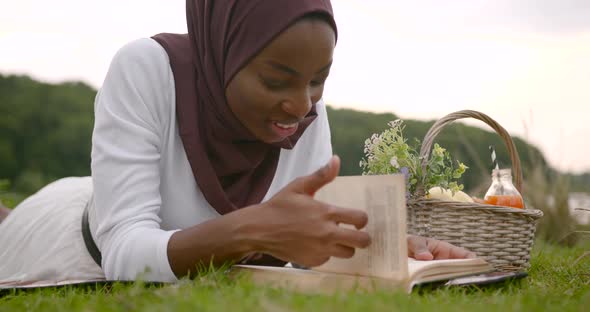 Black Woman in White Dress Reading at the River Bank