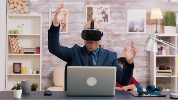 Senior Man Using Virtual Reality Goggles in Living Room