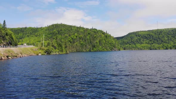 Drone footage flying quickly out over the middle of a lake with forest-covered mountains in the back