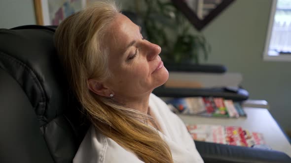 Mature woman is very happy while she gets her toenails clipped by pedicurist. Steadicam shot.