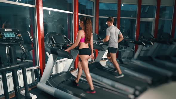 Attractive Young Couple Working Out Together at the Gym on Treadmills. Man and Woman Are Doing