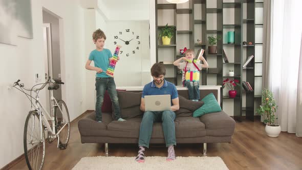 Young Father Looks After The Children At Home And Works At The Computer.