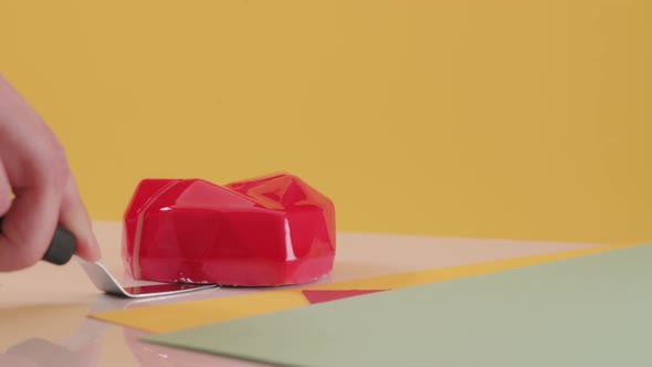 Pastry Chef Cuts Red Cake in the Form of Heart on Colored Yellow Background