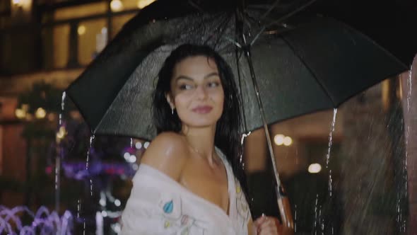 Portrait of Wet Brunette Stands Under Black Umbrella During Night Rain