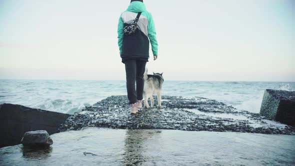 Young Beautiful Female Walking with Siberian Husky Dog on the Beach at Sunset Slow Motion