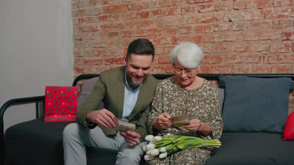 Caucasian Elderly Pensioner Mother and Her Middleaged Son Celebrating Mother's Day Sitting on a