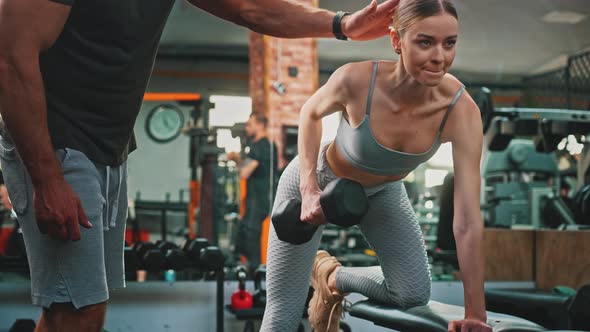 Focused Strong Beautiful Woman in Her 20s Doing Carefully Some Exercise at a Gym with a Personal