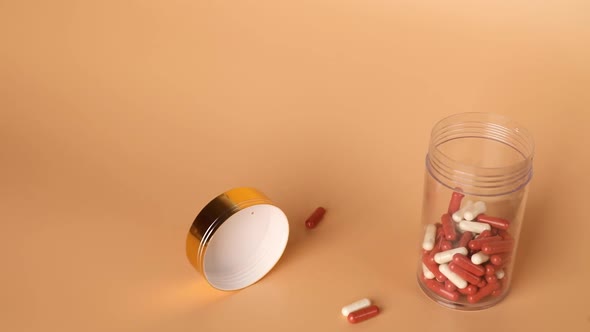 Red and white pills and tablets falling out of a bottle on table, pharmaceutical industry