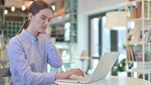 Young Businesswoman with Neck Pain Using Laptop in Cafe