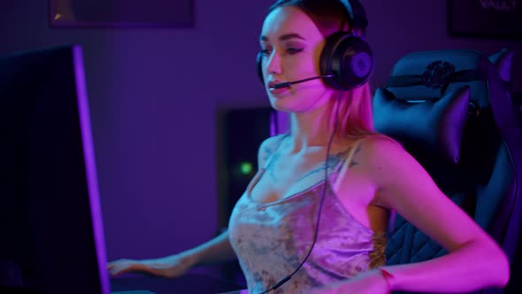 Tattooed Gamer Girl in Big Headphones Sitting By the PC