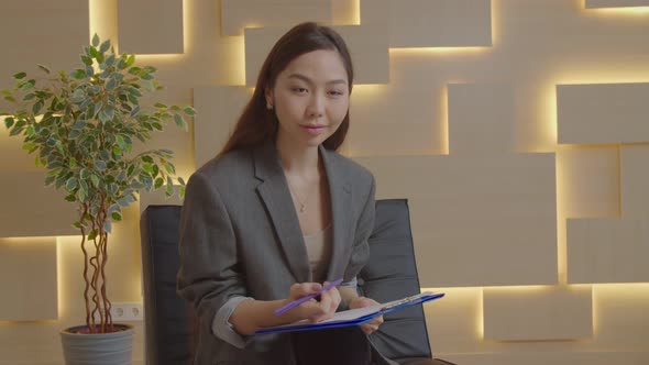 Attentive Asian Female Psychotherapist Working with Patient and Taking Notes