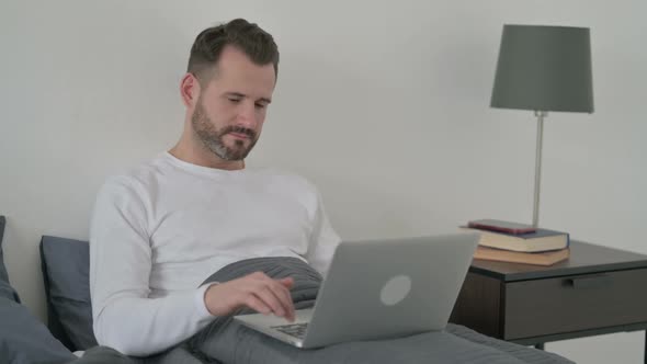 Man with Laptop Saying No By Head Shake in Bed