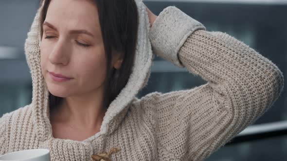 Woman Stays on Balcony During Snowfall with Cup of Hot Coffee or Tea