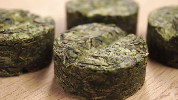 Herbal pills of pressed braided herbs on a wooden surface. Dried green tea leaves