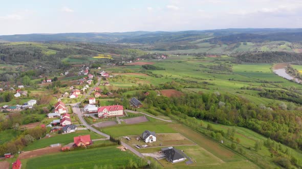 Aerial Drone View of Green Fields, Hills and Trees in a Village with Small Houses. Poland.