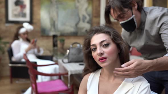 Hairdresser wearing protective mask and preparing bride for wedding