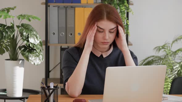 Stressed young red hair female student suffering from headache