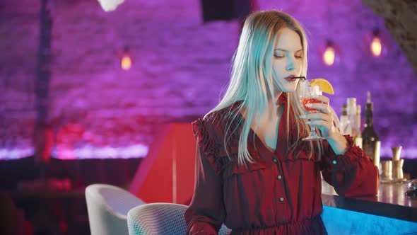 Gorgeous Young Woman Sitting By the Bartender Stand Drinking a Cocktail, Turning Around and Turning