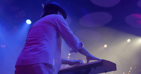 A Young Man Plays a Synthesizer on Stage