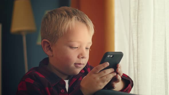 Little Boy Using Smartphone Playing Games Relaxing at Home Child Browsing Online with Mobile Phone alt